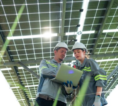 A team of electrical engineers is inspecting and maintaining solar panels at a solar panel site in the middle of a hundred acre field.
