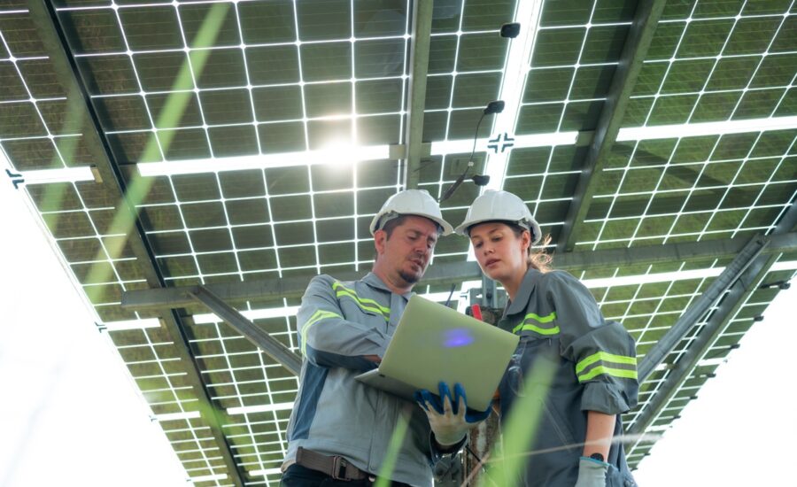 A team of electrical engineers is inspecting and maintaining solar panels at a solar panel site in the middle of a hundred acre field.