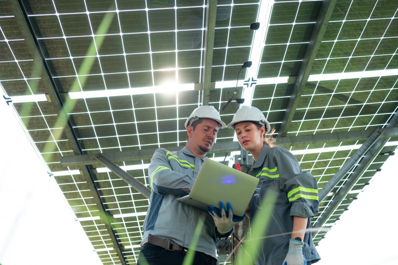 A team of electrical engineers is inspecting and maintaining solar panels at a solar panel site in the middle of a hundred acre field.